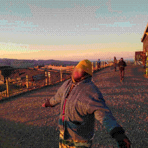Picture of me with blurred face yellow beanie, in almost T-pose, enjoying the sunrise